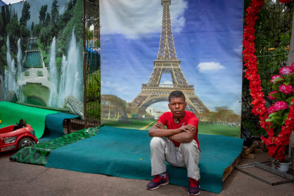 Photographie de Madagascar. Un jeune homme devant une image de la Tour Eiffel, décors pour les photos de fête. Antananarivo.