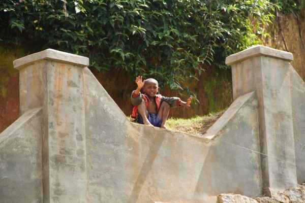 Photographie de Madagascar. Enfant sur un gros mur, qui salue le passage du Train de la FCE.