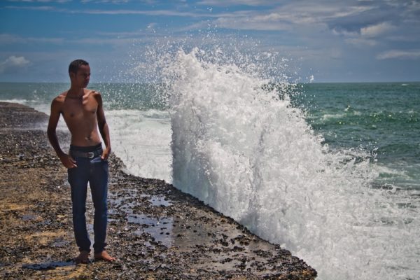 Photographie de Madagascar. Max Razafitiamanana sur le front le mer à Manakara, avec une vague aussi grande que lui.