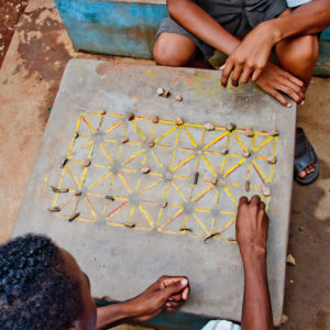 Photographie de Madagascar. Le jeux Fanorona. Des écoliers réfléchissent en pleine rue à Tsiroanomandidy