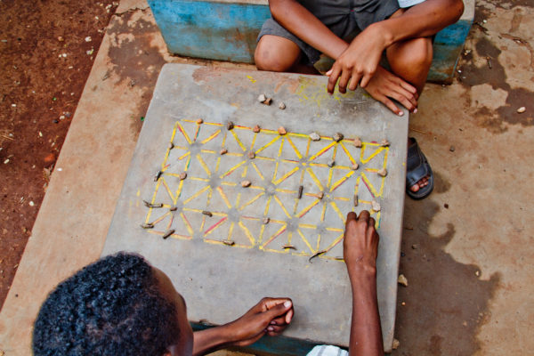 Photographie de Madagascar. Le jeux Fanorona. Des écoliers réfléchissent en pleine rue à Tsiroanomandidy