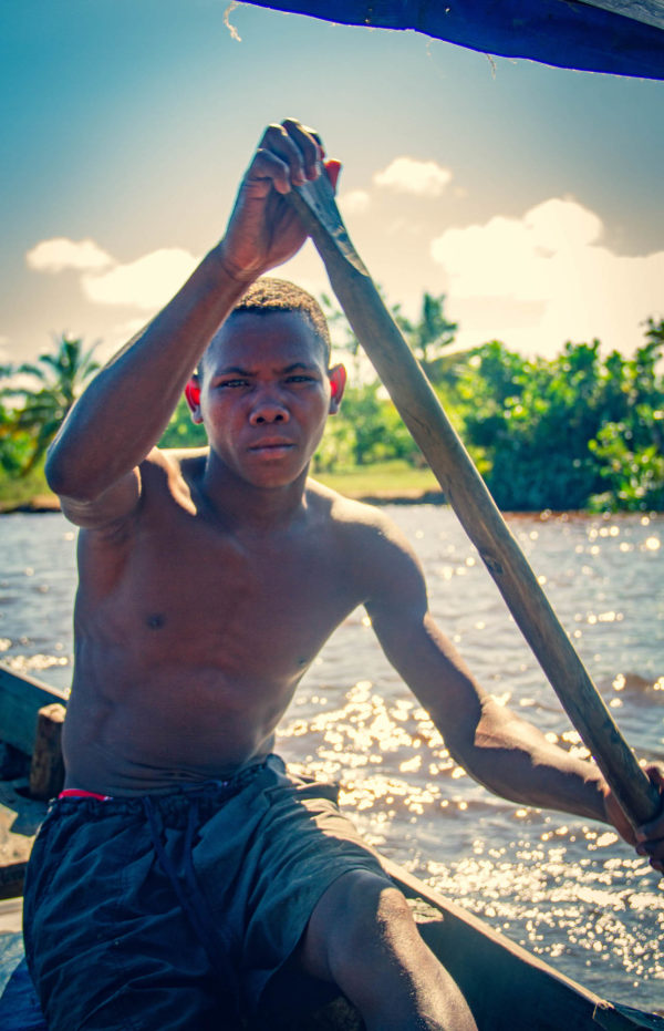 Photographie de Madagascar. Canal des Pangalanes à Manakara. Jeune piroguier en plein effort, très proche, depuis l'embarcation dans laquelle ile pagaie.