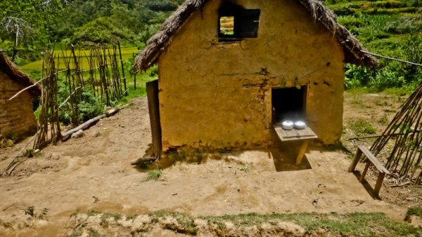 Photographie de Madagascar. Photographie depuis le train de la FCE. Vue plongée sur une maison très rudimentaire, avec 2 marmites en alluminium qui brillent au soleil.